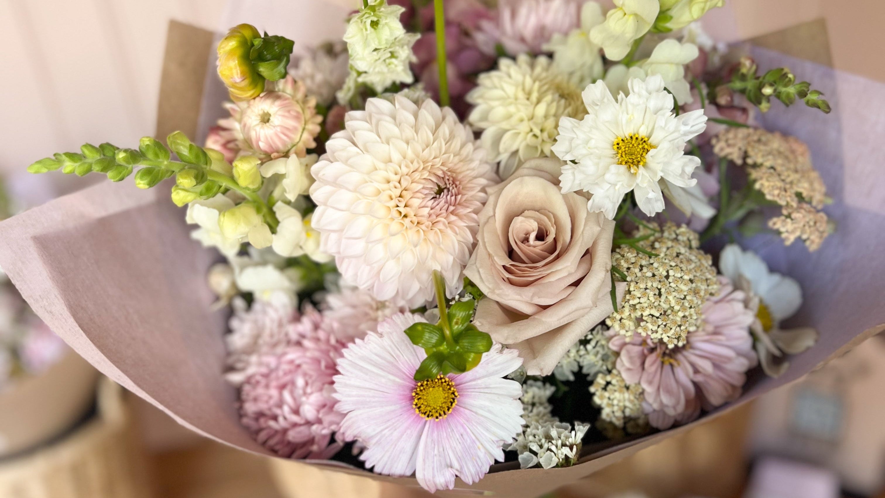 Bouquet of boutique flowers held by a person with more bouquets in the background